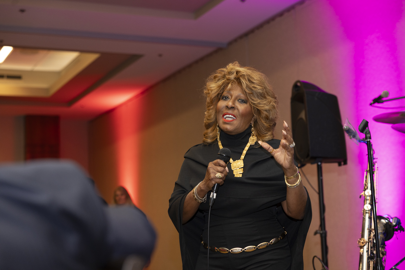 Marcia Griffin speaking with a handheld microphone at an evening event